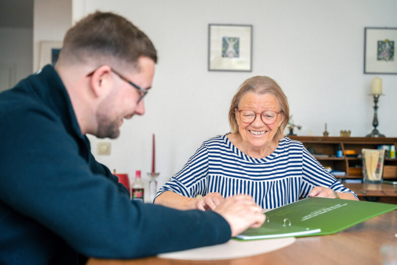 Szene: Mitarbeiter des Seniorenservice im Gespräch mit einer Klientin am Tisch